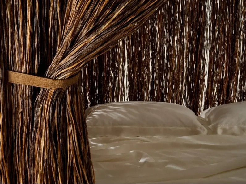 Letto di design con baldacchino ispirato alle capanne primitive Cabana Bed rivestito con lunghissimi fili stratificati di spessa rafia sintetica con cinturini in pelle di Edra